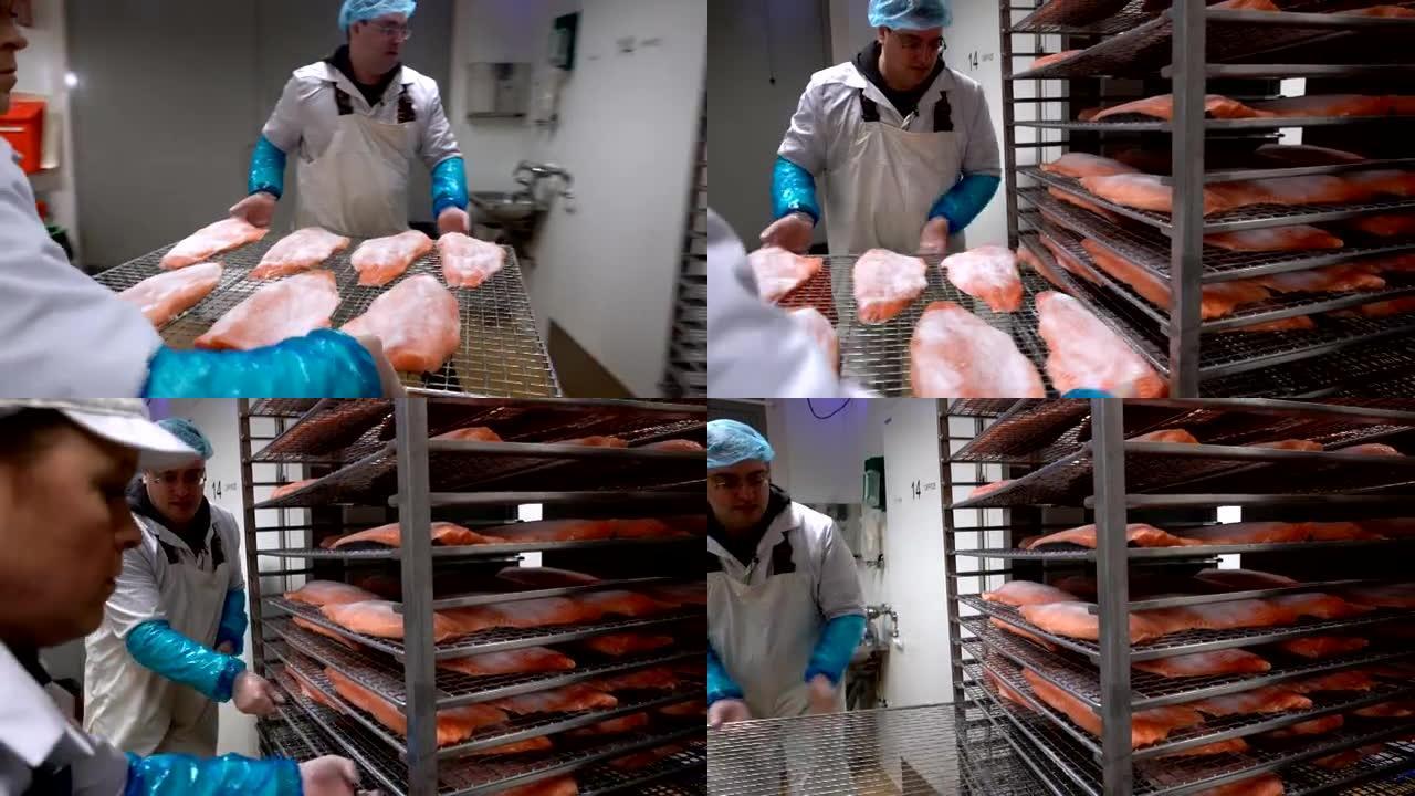 一名工人将鲑鱼片放入烤箱中，以便在工厂里抽烟。