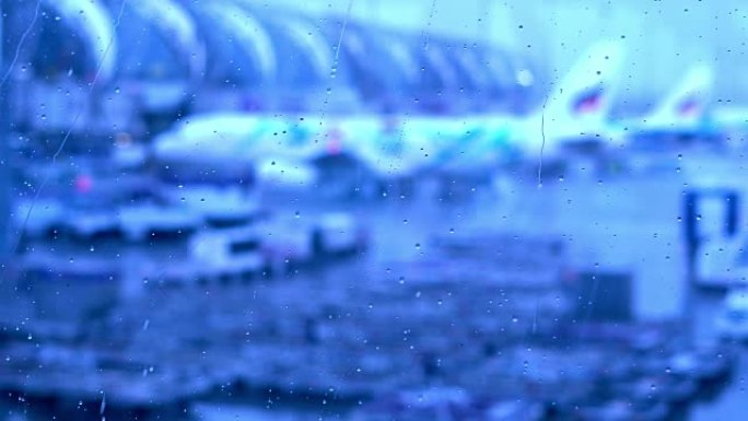 机场航站楼窗户上的雨滴，外面模糊机场