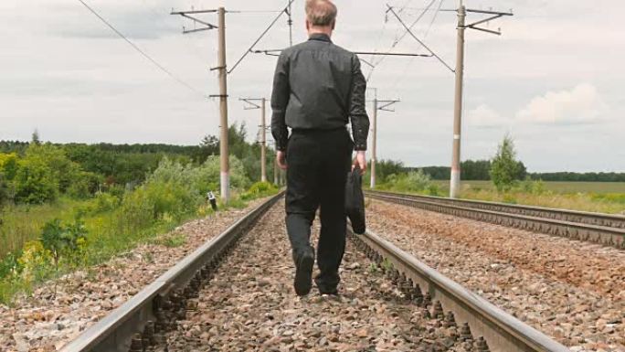 一个穿着商务服装的男人正在铁轨上行走。