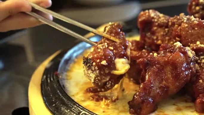 用筷子手拿融合食物亚洲辣鸡肉和西方融化奶酪