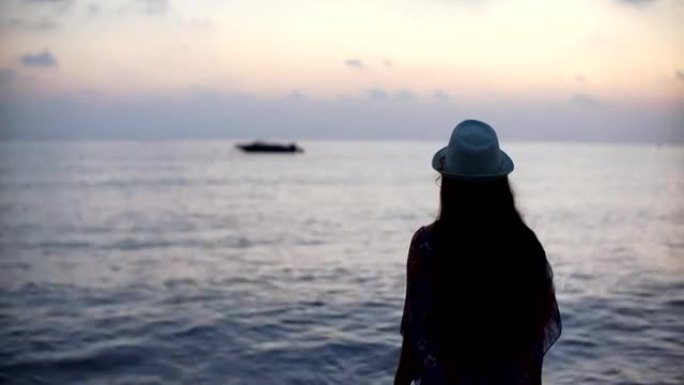 日落时海上背景下长发的年轻女子的剪影