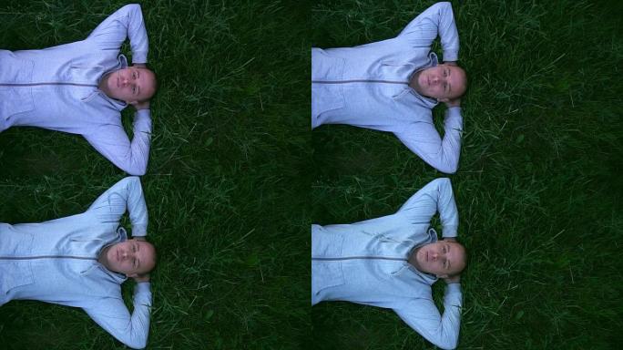 美丽的男人躺在草地上，嘴里拿着草。慢动作