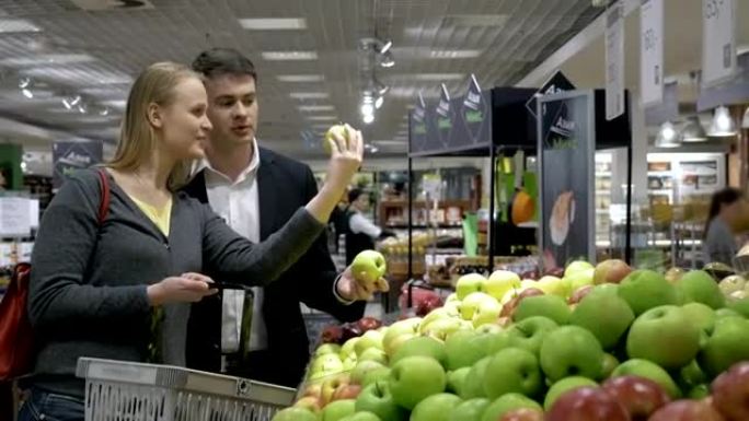年轻人在超市挑选苹果