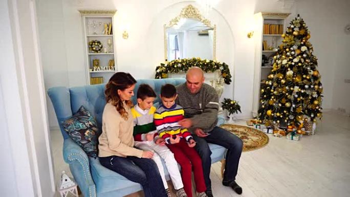 一家之主，父亲和丈夫在妻子和男孩之间分配家庭预算，白天坐在带有圣诞树和壁炉的节日装饰房间的蓝色沙发上