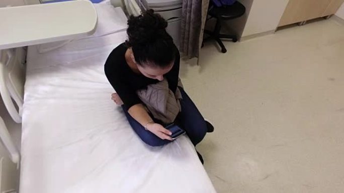 女患者在医院床上使用智能手机等待手术后出院