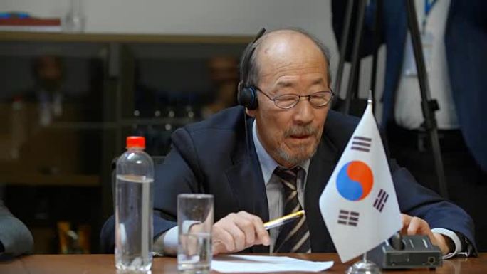一位年长的韩国代表正准备在一个重要的国际会议上发言