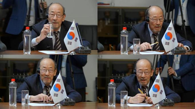 一位年长的韩国代表正准备在一个重要的国际会议上发言