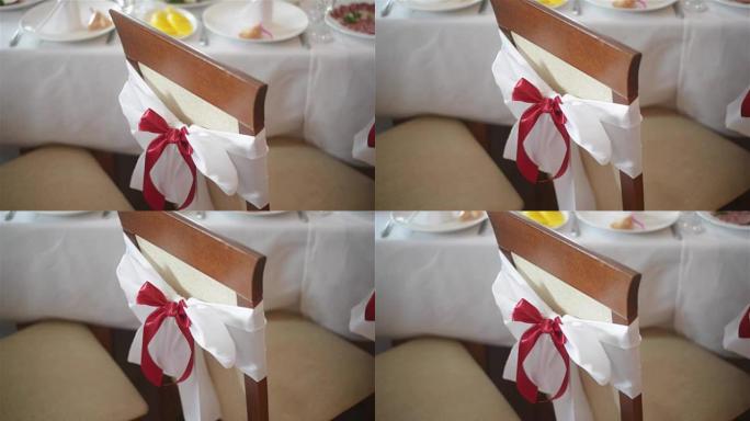 在婚宴或招待会上，带红色蝴蝶结的白色椅子在室内关闭。婚礼装饰品。大日子。