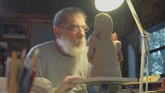 老雕塑家在他的小工作室里做泥塑