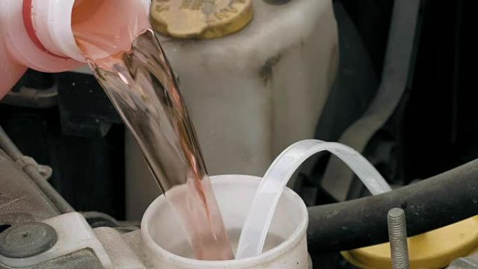 将粉红色的挡风玻璃清洗液倒入汽车中