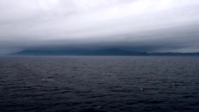 海洋海水波浪表面和沿海岩石礁海岸云层。日落时间前后多云。