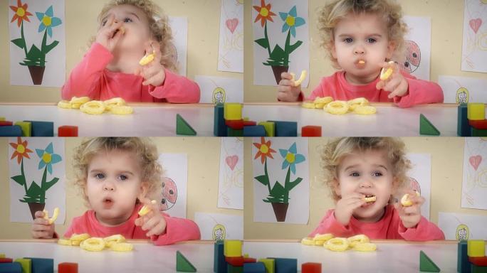 饥饿的孩子在他房间的桌子旁吃玉米薯片