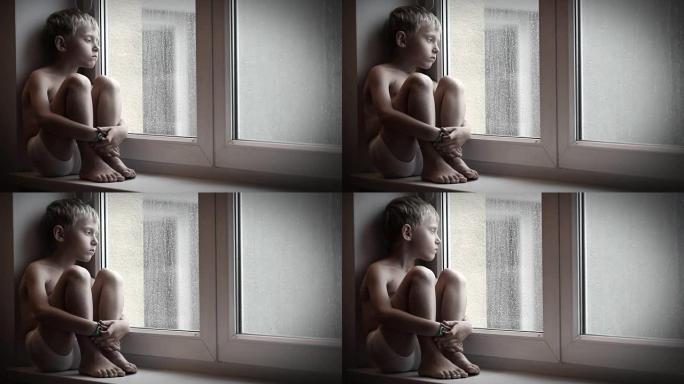 喜怒无常的小男孩坐在窗台上，看着雨滴从窗玻璃上掉下来