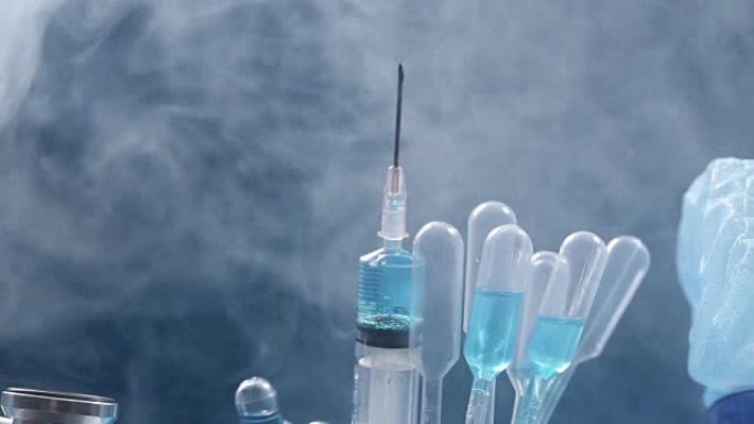 玻璃管测试实验室中的蓝色液体，滴管，注射器，模糊头盔，听诊器，手套和护目镜，在设备机器上旋转的管