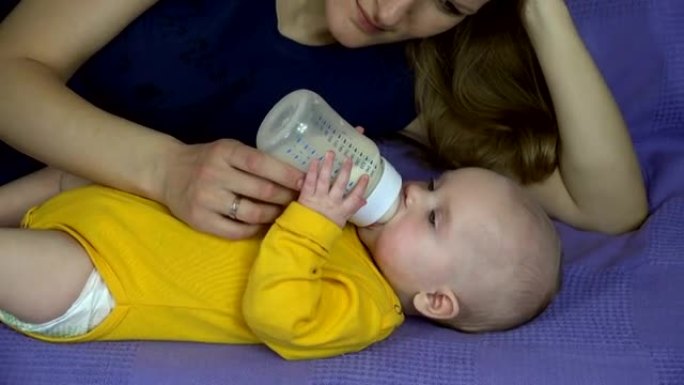 慈爱的母亲用奶粉瓶喂养新生女孩。全高清