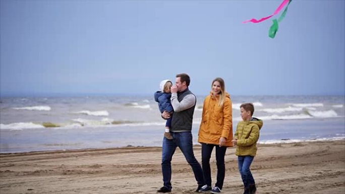 幸福的家庭，有两个孩子，在沙滩上放风筝，享受周末