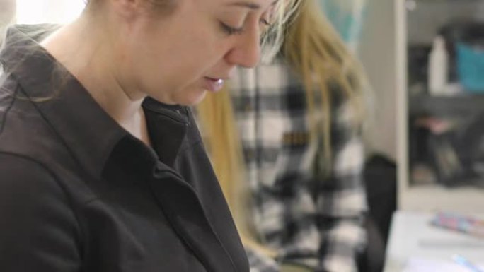 穿着黑色衬衫的女人在创意办公室手里拿着一个色轮。女化妆师在大师班上教授化妆技巧。