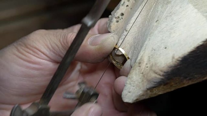 在金戒指上进行切割: 使用金属切割机的金匠