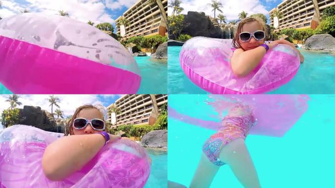 可爱的金发女孩带着充气玩具在度假游泳池游泳