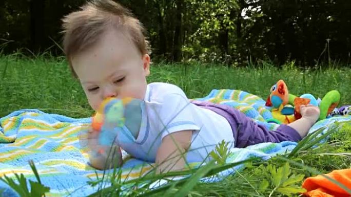 可爱的唐氏综合症男婴的肖像躺在玩具上的毯子上
