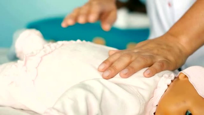 一只手压迫婴儿训练娃娃进行心肺复苏术的妇女