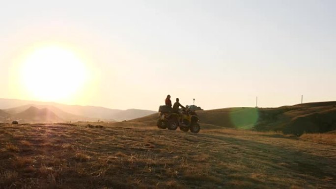一对年轻游客的无人机在乘坐ATV运输工具时，正在缓慢地在日落时欣赏美丽的海景。夫妇正在海边的山上骑四