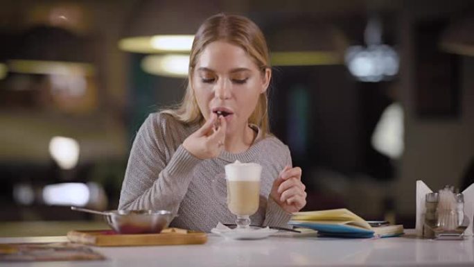 一个年轻漂亮的女人在一家餐馆喝乳胶咖啡，一位女士吃牛奶，喝牛奶，旁边放着一个笔记本