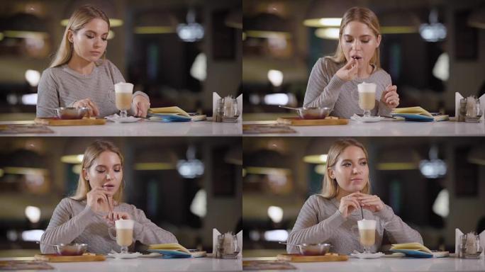 一个年轻漂亮的女人在一家餐馆喝乳胶咖啡，一位女士吃牛奶，喝牛奶，旁边放着一个笔记本