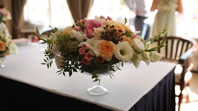 婚礼或生日餐厅室内装饰的特写镜头，颜色为白色和蓝色。接待和宴会前咖啡馆餐桌上的假日花店或玫瑰