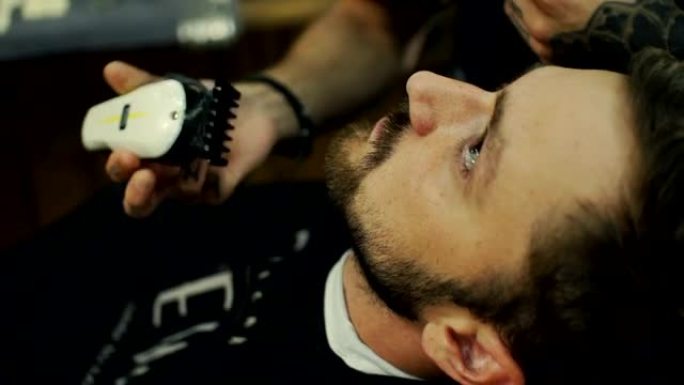 变得完美。理发店理发师给年轻大胡子男人理发的特写侧视图