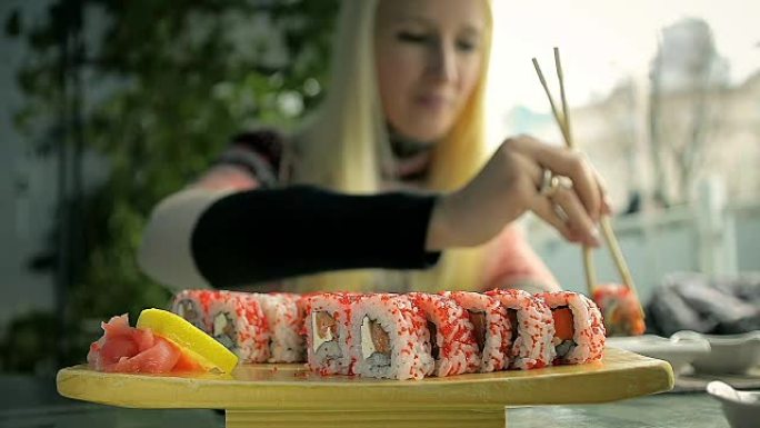 在日本餐馆用筷子吃寿司的女孩