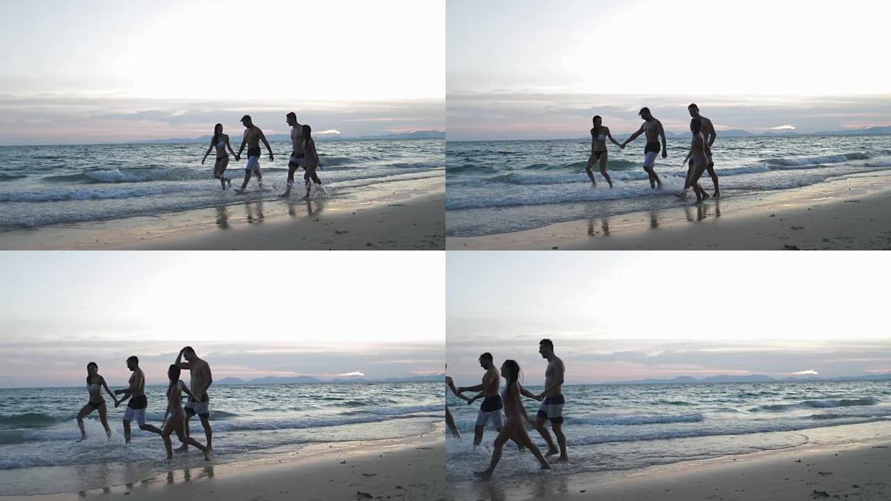 两对幸福的夫妻在日落时牵手在沙滩上散步，年轻人游客在暑假中交流