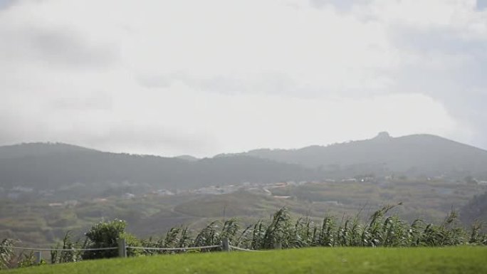 绿色的田野，山脉和灰色的夏日天空，云彩。大风天气。葡萄牙Cabo da roca汽车站的景观