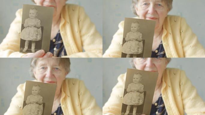 老年妇女翻阅旧照片相册一名老年妇女举着自己小时候的旧照片