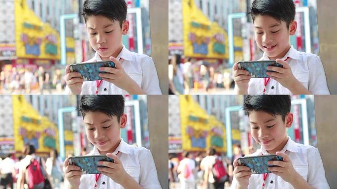 快乐亚洲男孩在步行街附近使用智能手机