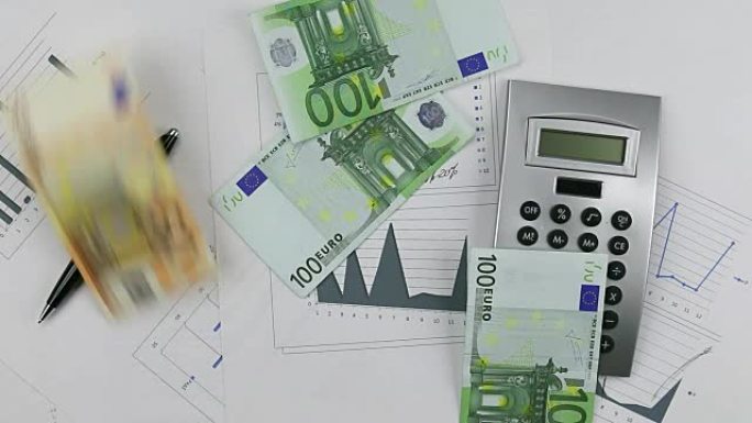 用计算器和笔在图表上扔欧元。把钱扔下桌子