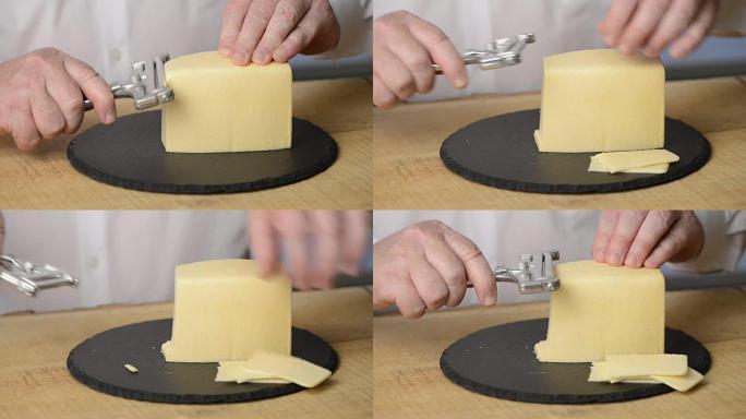该男子在板岩的黑色圆形砧板上使用奶酪切片机将奶酪切成薄片