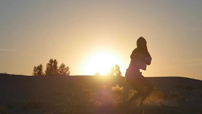 一个女孩专业舞者在日落时以慢动作跳跃的剪影