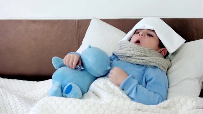 生病的样子，嗓子疼的小男孩，婴儿测量温度电子温度计，孩子脖子上围着围巾躺在床上