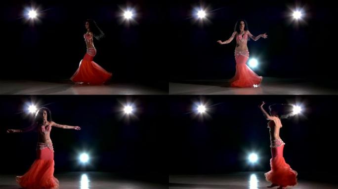 一位欧洲女肚皮舞演员在黑色，背光，慢动作上跳舞