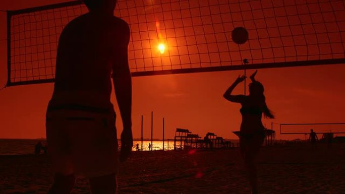 日落时沙滩排球运动员的剪影