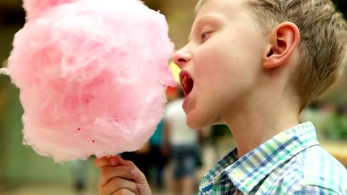 一个小男孩用食欲不振的粉红色糖果牙线的慢动作镜头