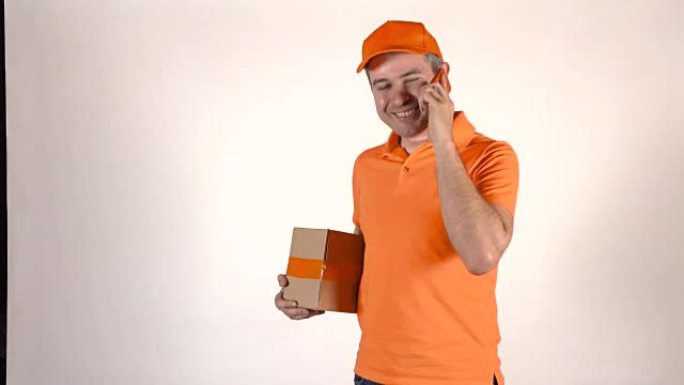 穿着橙色制服的帅哥在手机上聊天，送包裹。浅灰色背景，全高清工作室照明镜头