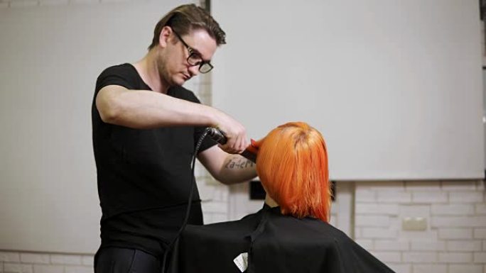 一个女人在发廊里被男性专业发型师拉直头发的特写镜头。4k拍摄