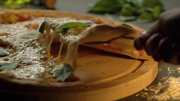 至尊美味披萨提起切片，融化奶酪和罗勒叶放在木制切菜板上，慢动作。