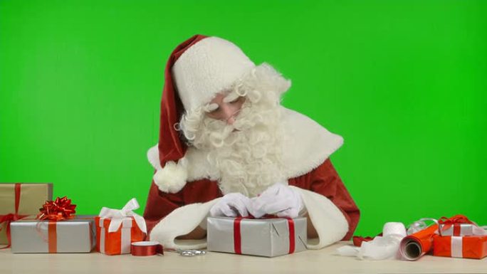 圣诞老人正在用银色纸包装礼物