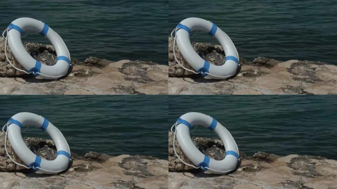 一个白色的救援浮标靠在水边的一块石头上