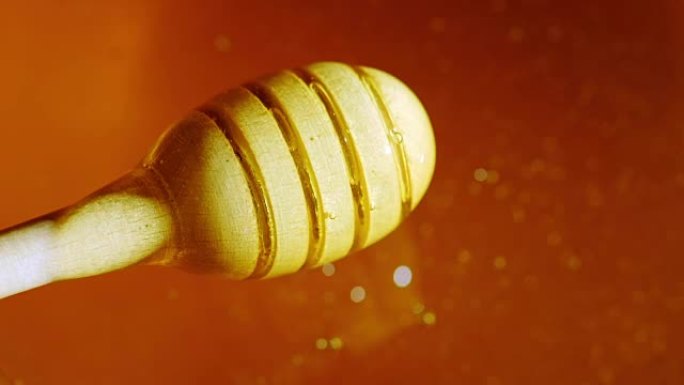 慢慢旋转一个装蜂蜜的木勺。纯正新鲜蜂蜜发光滴落