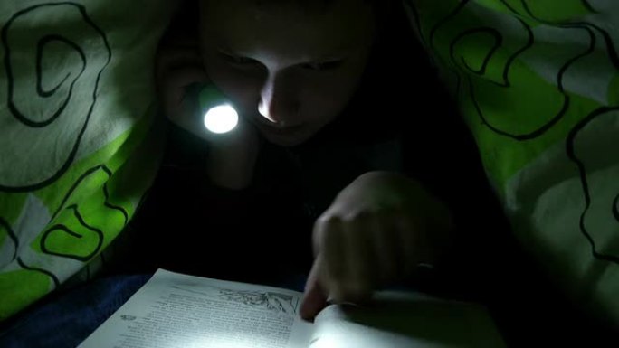 男孩在卧室里用手电筒看书