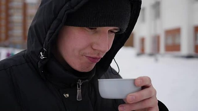 这家伙在冬天的户外喝杯子里的热茶。特写